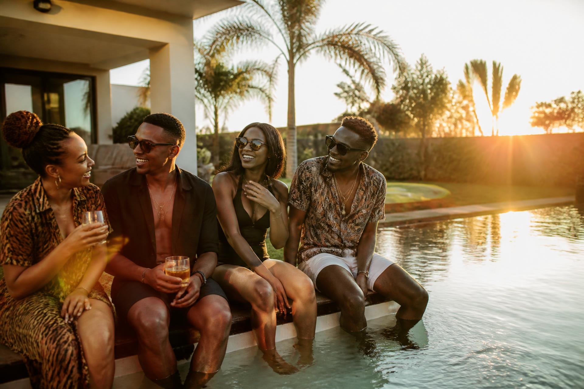 Friends laughing by an infinity pool at sunset in Lusaka
